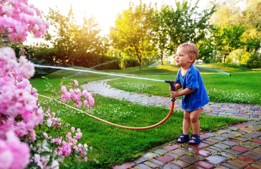 toddler in garden watering plants