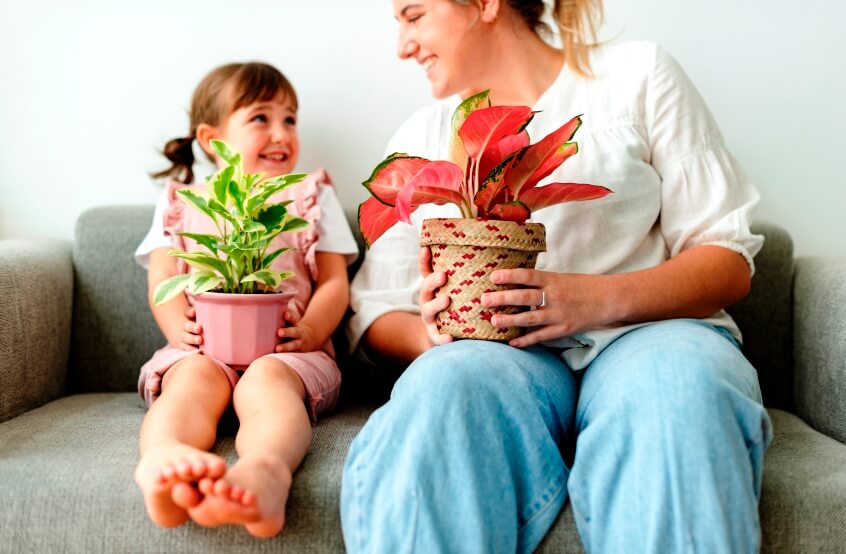 kid and mother holding potted aglaonema plants